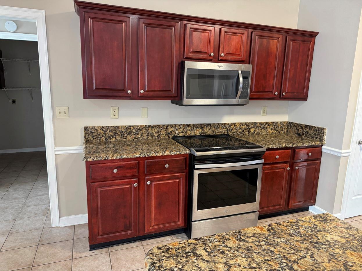 8810 Raspberry Lane Memphis, TN 38016 - Photo 8 of 28 Kitchen with light tile patterned floors, appliances with stainless steel finishes, dark stone countertops, and reddish brown cabinets