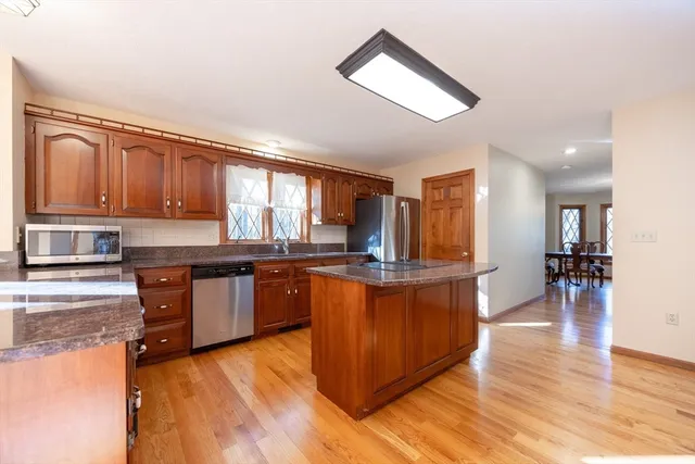 a large kitchen with stainless steel appliances granite countertop a stove and a wooden floors