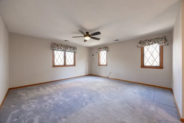 an empty room with windows and ceiling fan
