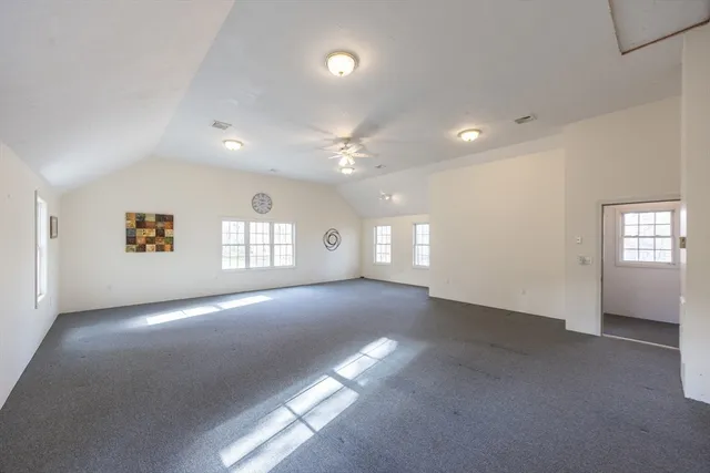 an empty room with windows and ceiling fan