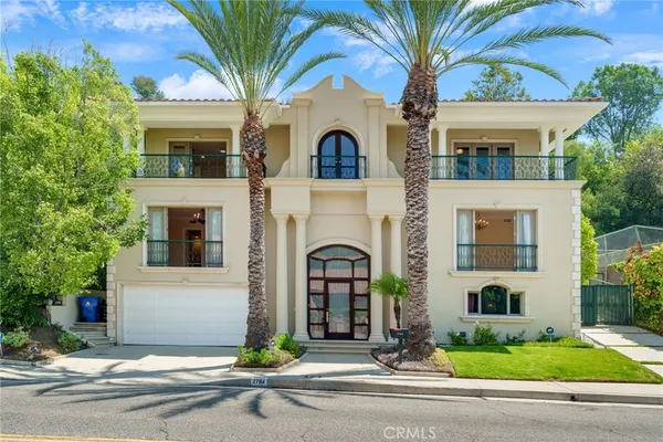 a view of a white house with large windows and a small yard