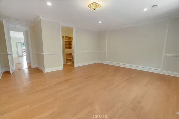 an empty room with wooden floor and entryway