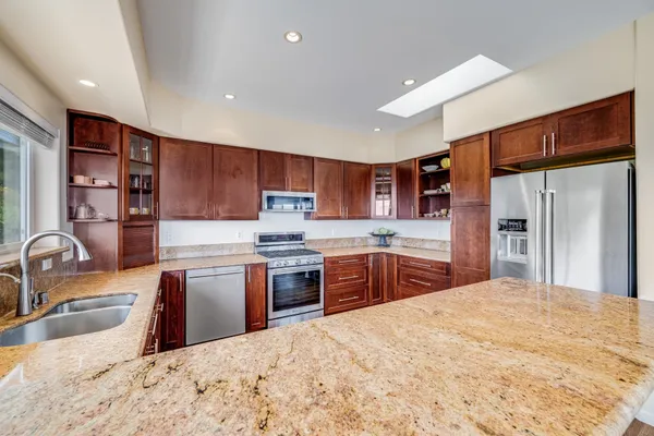 a kitchen with stainless steel appliances kitchen island granite countertop a sink refrigerator and cabinets