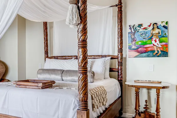 a bedroom with a bed and painting on the wall