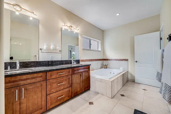 a bathroom with a sink double vanity mirror and a bathtub
