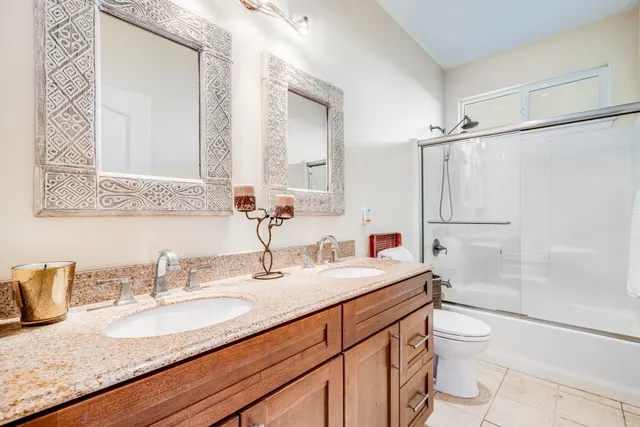 a bathroom with a granite countertop sink a toilet a mirror and shower
