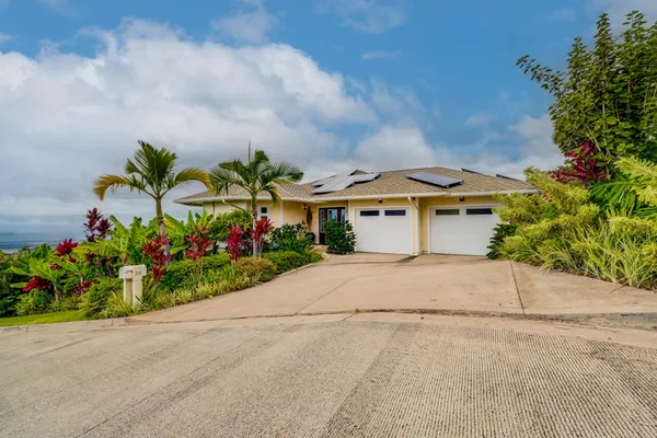 a front view of a house with a yard and a garden