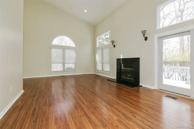 an empty room with wooden floor fireplace and windows