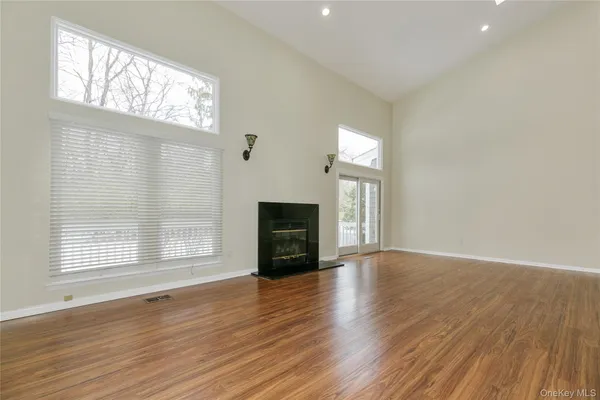 an empty room with wooden floor fireplace and windows