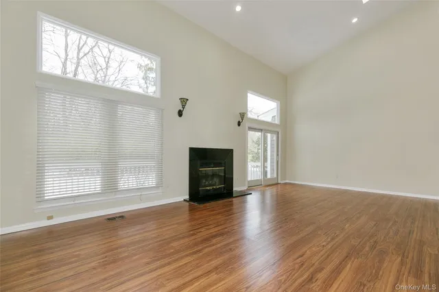 an empty room with wooden floor fireplace and windows