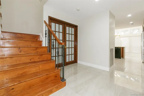 an empty room with wooden floor chandelier and windows