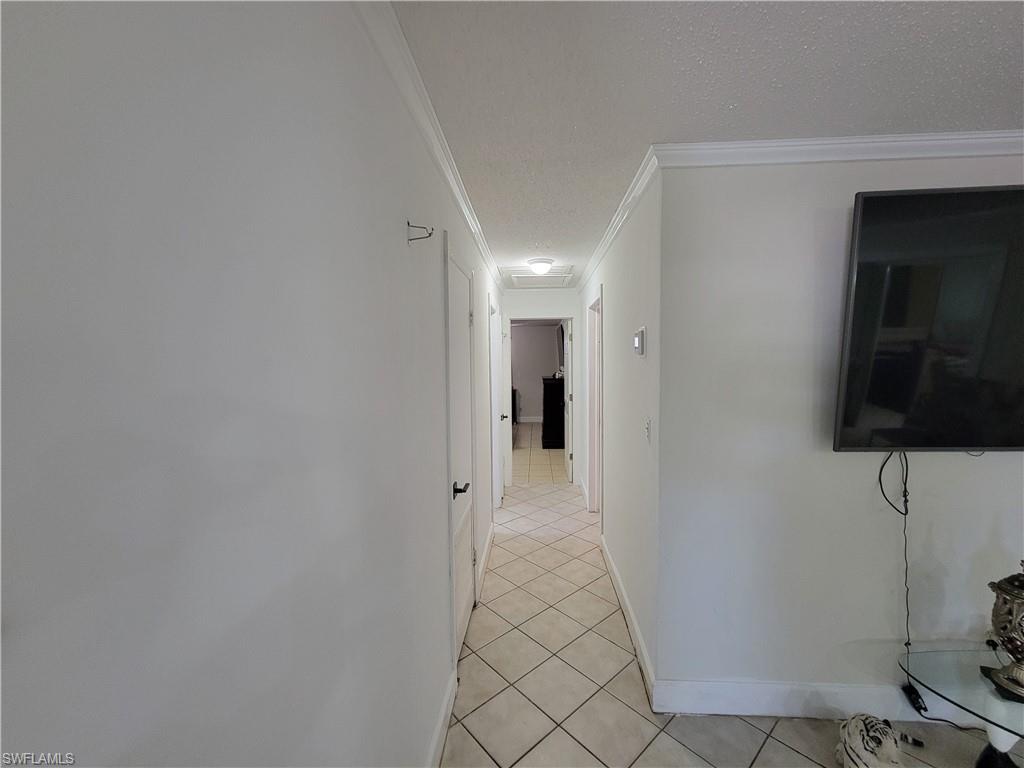 10 East Jersey Road Lehigh Acres, FL 33936 - Photo 14 of 32 Corridor featuring crown molding, light tile patterned floors, baseboards, and a textured ceiling