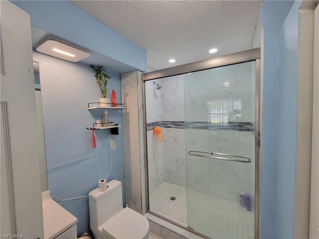 10 East Jersey Road Lehigh Acres, FL 33936 - Photo 16 of 32 Bathroom with recessed lighting, a textured ceiling, toilet, and a marble finish shower