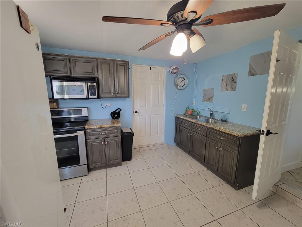 10 East Jersey Road Lehigh Acres, FL 33936 - Photo 18 of 32 Kitchen with ceiling fan, a sink, light stone counters, and appliances with stainless steel finishes