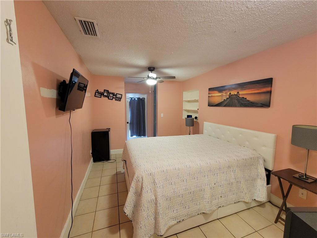 10 East Jersey Road Lehigh Acres, FL 33936 - Photo 21 of 32 Bedroom with visible vents, a textured ceiling, a ceiling fan, and light tile patterned flooring