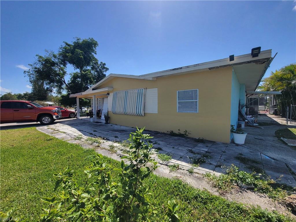10 East Jersey Road Lehigh Acres, FL 33936 - Photo 28 of 32 View of side of home with a patio area, stucco siding, and a lawn
