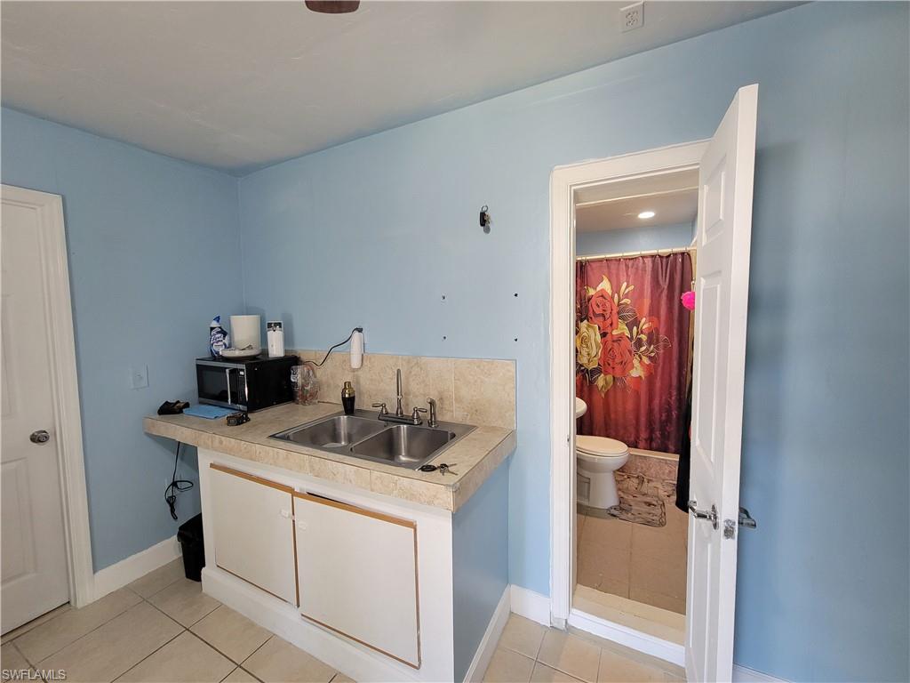 10 East Jersey Road Lehigh Acres, FL 33936 - Photo 30 of 32 Kitchen featuring a sink, light tile patterned floors, black microwave, and light countertops
