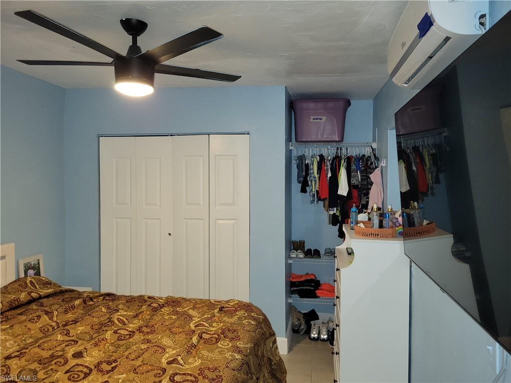 10 East Jersey Road Lehigh Acres, FL 33936 - Photo 31 of 32 Bedroom featuring a ceiling fan, tile patterned floors, a closet, and an AC wall unit
