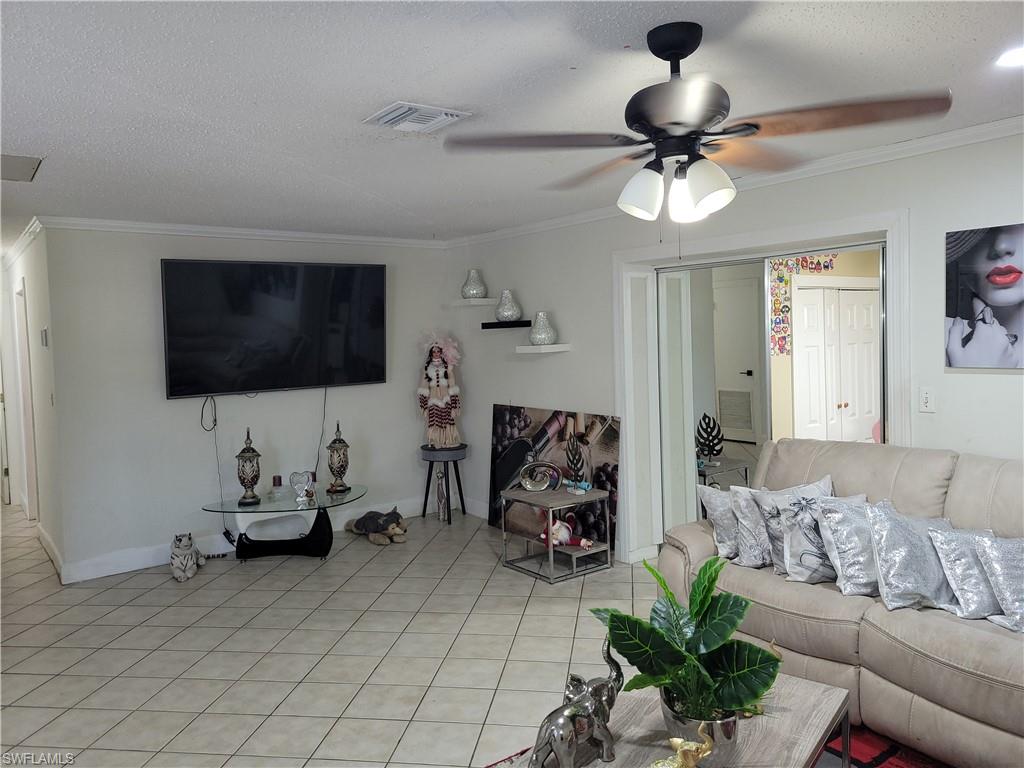 10 East Jersey Road Lehigh Acres, FL 33936 - Photo 8 of 32 Living area with visible vents, ceiling fan, a textured ceiling, crown molding, and light tile patterned flooring