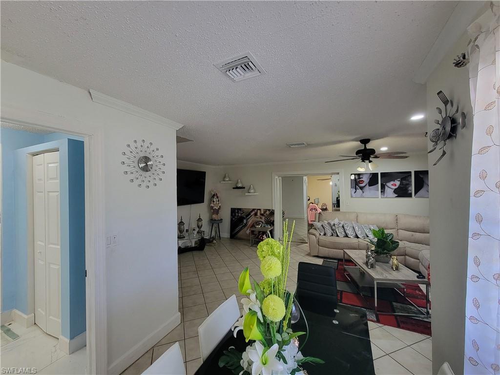 10 East Jersey Road Lehigh Acres, FL 33936 - Photo 9 of 32 Living room with a textured ceiling, light tile patterned floors, ceiling fan, and visible vents