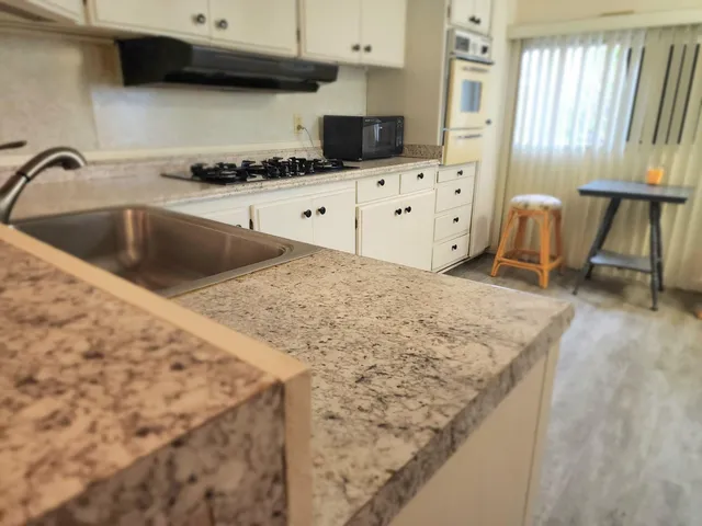 a kitchen with granite countertop a sink a stove and a microwave oven