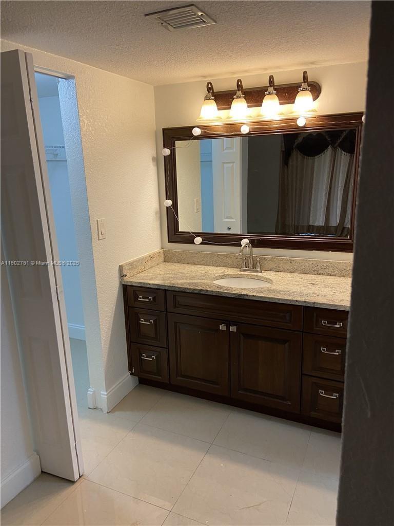 3955 North Nob Hill Road, Unit 101 Sunrise, FL 33351 - Photo 14 of 19 a bathroom with a double vanity sink and mirror