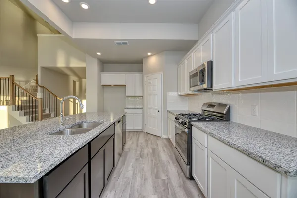 a kitchen with stainless steel appliances granite countertop a sink stove microwave and cabinets