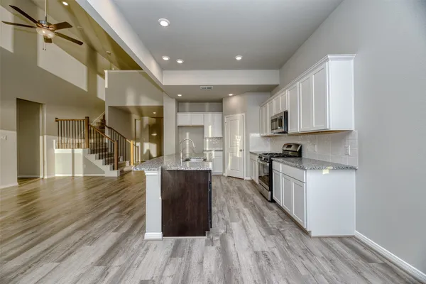 a kitchen with stainless steel appliances granite countertop a stove top oven a sink dishwasher a refrigerator and cabinets with wooden floor