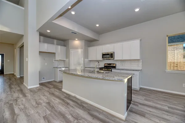 a kitchen with stainless steel appliances granite countertop a sink a stove a refrigerator cabinets and a center island