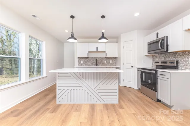 a kitchen with stainless steel appliances granite countertop a stove a sink and a wooden floor