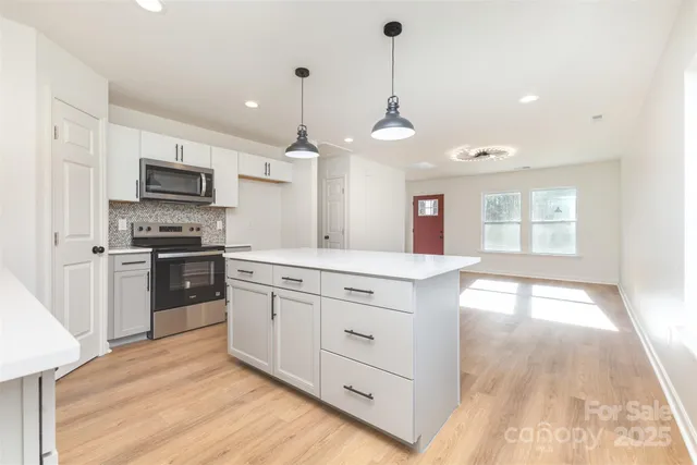 a kitchen with stainless steel appliances kitchen island granite countertop a stove a sink and a refrigerator