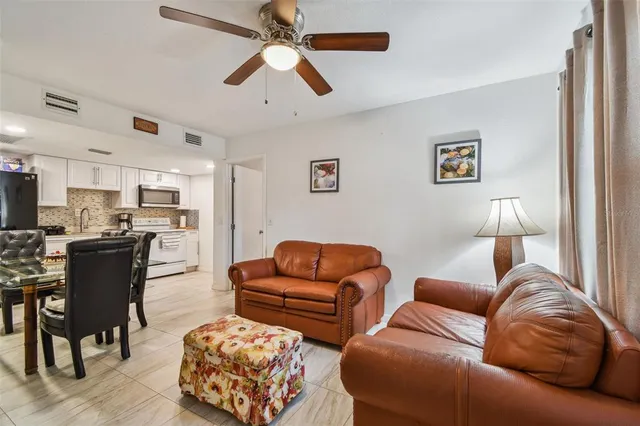 a living room with furniture kitchen view and a wooden floor