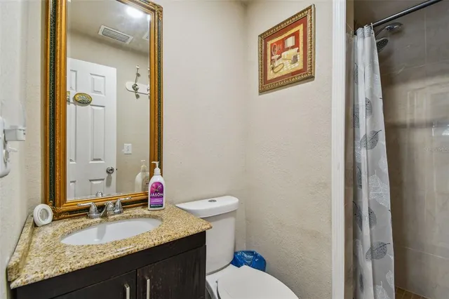 a bathroom with a granite countertop sink toilet and shower