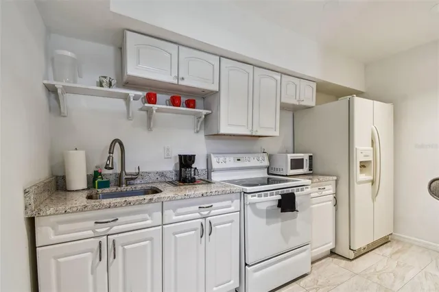 a kitchen with granite countertop white cabinets and white appliances
