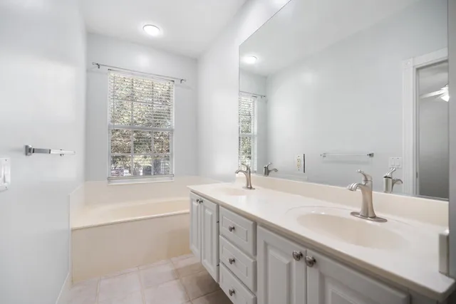 a bathroom with a sink double vanity granite tub shower and a mirror
