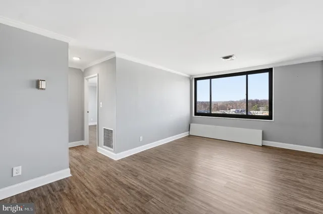 a view of an empty room with wooden floor and a window