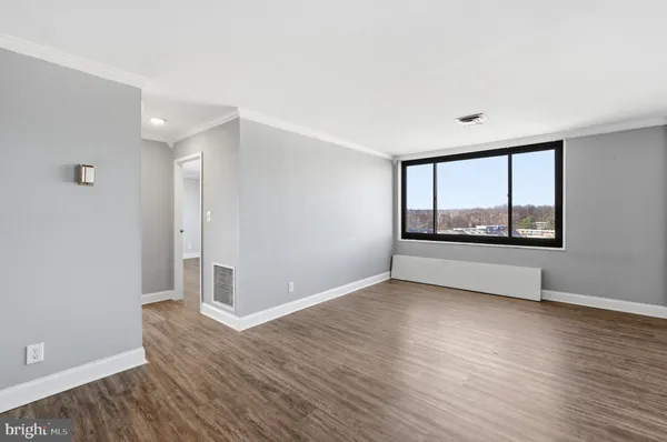 a view of an empty room with wooden floor and a window