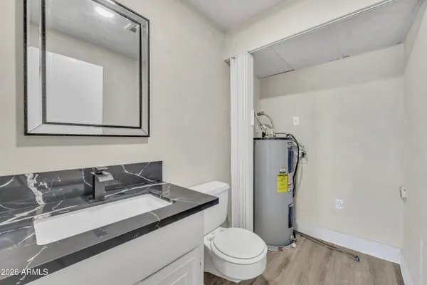 a bathroom with a granite countertop sink toilet and mirror