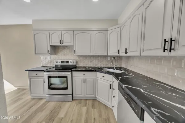 a kitchen with granite countertop white cabinets and appliances