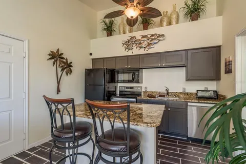 a kitchen with stainless steel appliances granite countertop a table chairs stove and refrigerator