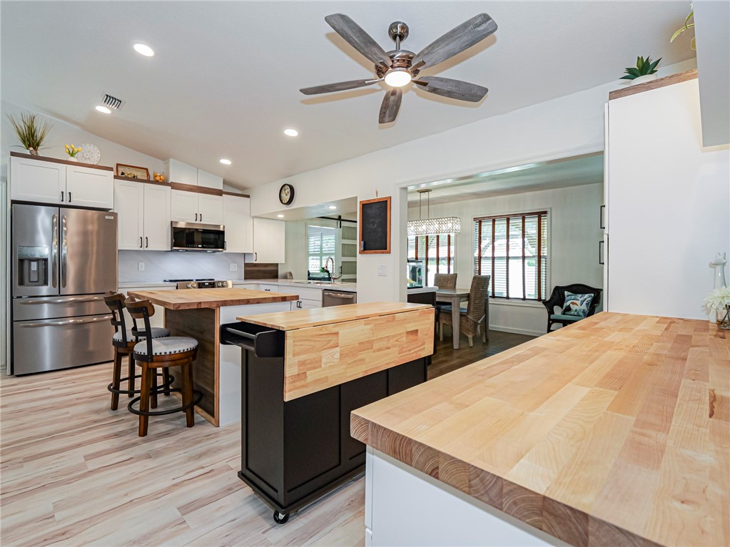 1732 Sunrise Lane Sebastian, FL 32958 - Photo 7 of 36 a large kitchen with kitchen island a stove a sink a refrigerator and a dining table with wooden floor