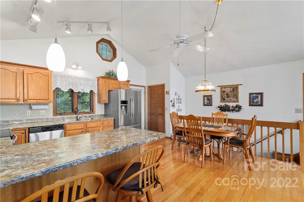 125 Rountoit Road Waynesville, NC 28786 - Photo 8 of 30 an open kitchen with granite countertop a stove a sink a dining table and chairs with wooden floor