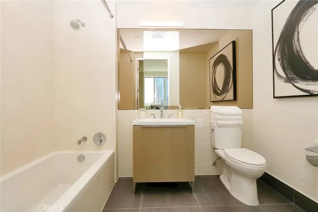a bathroom with a toilet sink vanity tub and mirror