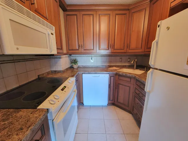 a kitchen with granite countertop a sink a stove and cabinets