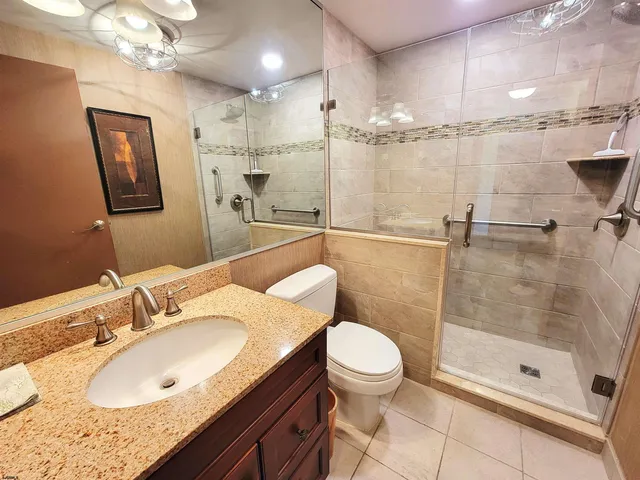 a bathroom with a granite countertop sink a toilet a mirror and shower