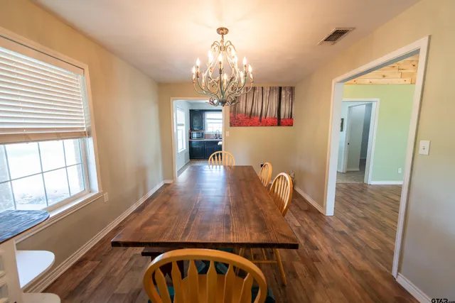 a dining room with wooden floor a chandelier a wooden table and chairs