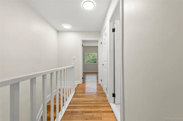 a view of a hallway with wooden floor and a bathroom