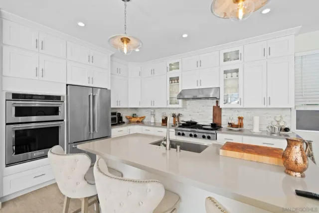 a kitchen with stainless steel appliances a stove a sink a microwave a refrigerator and white cabinets