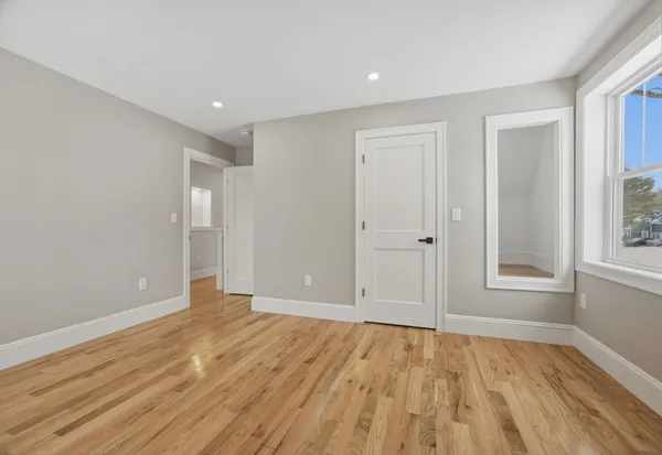 a view of an empty room with wooden floor and window