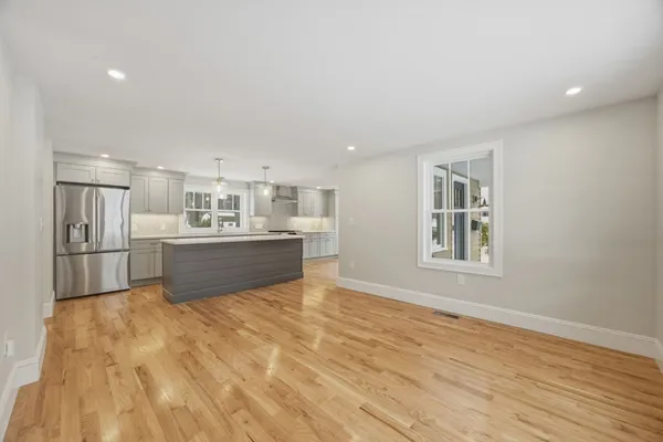 a view of kitchen and empty room with wooden floor